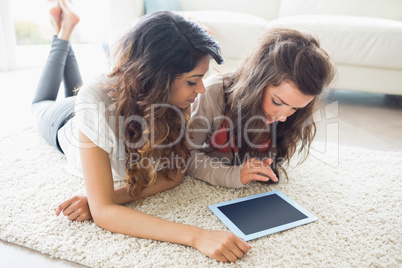 Two women looking at tablet pc on floor