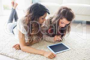Two women looking at tablet pc on floor