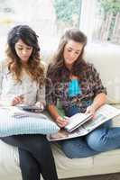 Two friends sitting on couch doing homework