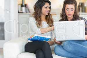 Girl pointing out something to friend on laptop