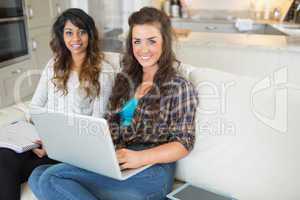 Happy girls using laptop for homework