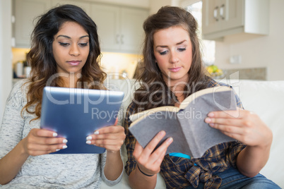 Girls reading a book and holding a tablet computer