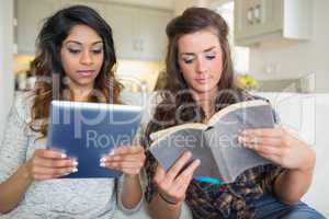 Girls reading a book and holding a tablet computer