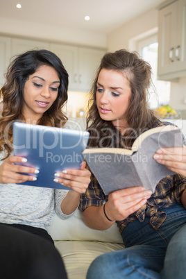 Women reading a book and holding a tablet computer