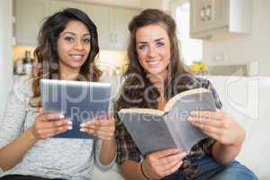 Smiling girls reading a book and holding a tablet computer