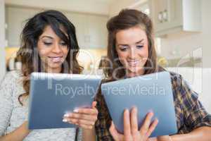 Two smiling women holding and looking at tablet computers