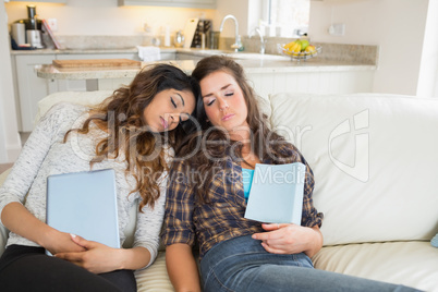 Women sleeping while holding tablet computers