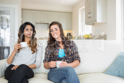 Two women drinking coffee on couch