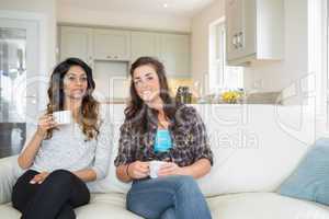 Two women drinking coffee on couch