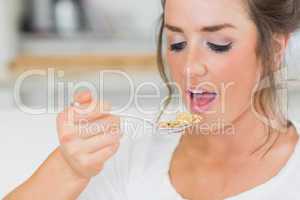 Girl lifting spoon of cereal to mouth