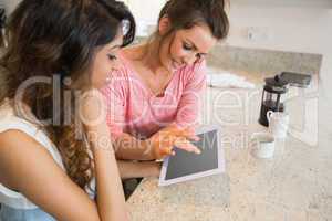 Smiling friends having coffee and using tablet computer