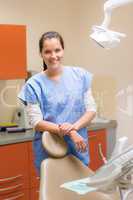 Female dentist standing behind patient chair