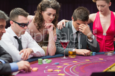 Man losing at poker table with woman comforting him