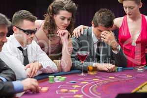Man losing at poker table with woman comforting him