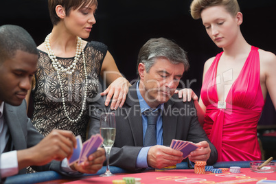 Man playing poker with two women beside him