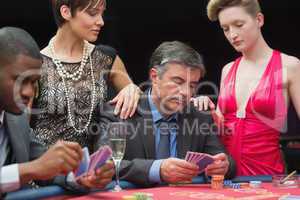 Man playing poker with two women beside him