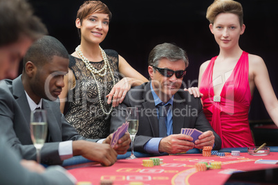 Man in sunglasses playing poker with two women either side