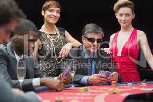 Man in sunglasses playing poker with two women either side