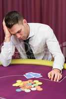 Man leaning on poker table looking disappointed