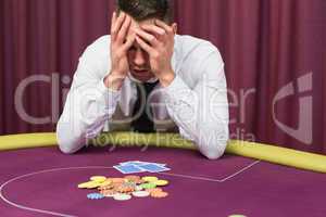 Man holding head in hands at poker table
