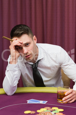 Worried man holding a cigar at poke at table