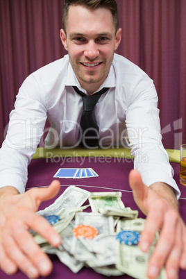 Happy man at poker table taking his winnings