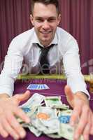 Happy man at poker table taking his winnings