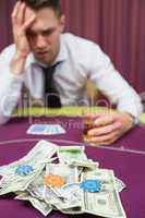 Man with whiskey glass leaning on poker table in casino