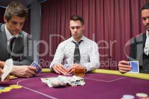 Men looking at their hands in high stakes poker game
