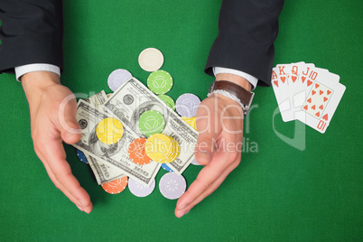 Hands grabbing dollars and chips from table beside royal flush