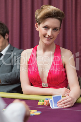 Woman sitting at the table holding cards smiling