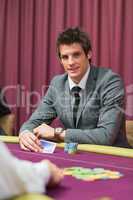 Man sitting at the table smiling while holding cards