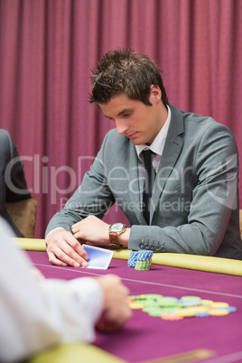 Man looking at his cards in poker game