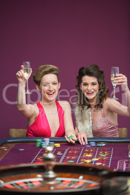 Women raising champagne glasses at roulette table