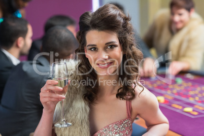Woman smiling raising her glass at roulette table