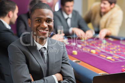 Smiling man sitting arms crossed at roulette table