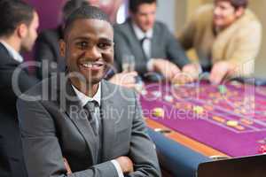 Smiling man sitting arms crossed at roulette table