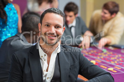 Smiling man sitting leaning on roulette table