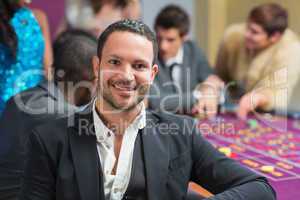 Smiling man sitting leaning on roulette table