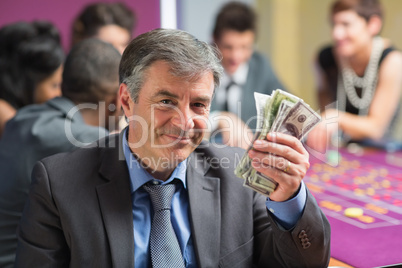 Man holding up money at roulette table