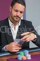 Man holding a cigar looking at his cards
