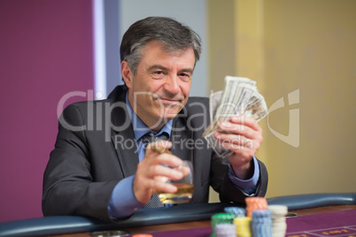 Man holding money smiling at roulette table