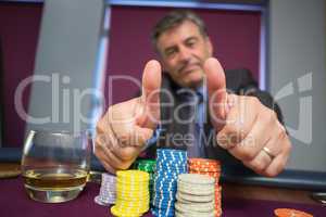 Man giving thumbs up sitting at roulette table