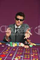 Man throwing chips on roulette table