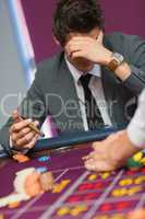 Man with cigar thinking at roulette table