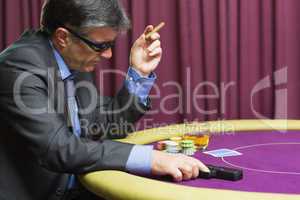Man with gun sitting at poker table