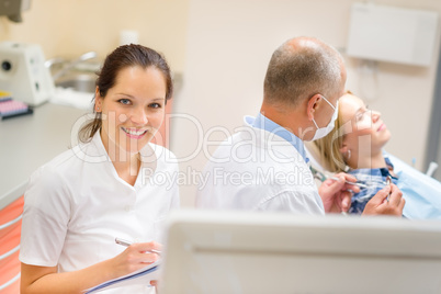 Smiling dental nurse prepare patient paperwork