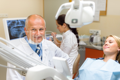 Friendly dentist with female patient dental office