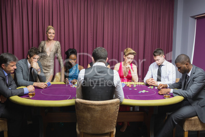 People sitting at the casino table with woman standing