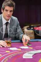 Man sitting at poker table with whiskey